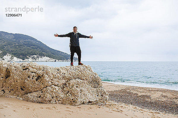 Italy  Vieste  relaxed man with arms outstretched standing on a rock on Vignanotica Beach