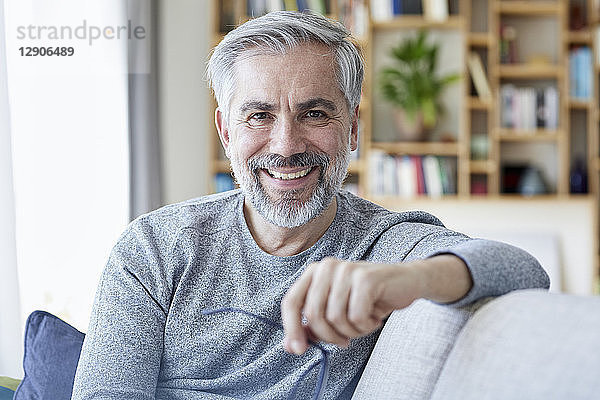 Portrait of smiling mature man sitting on couch at home