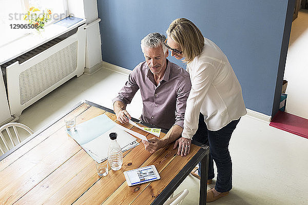 Mature couple with documents and tablet at home