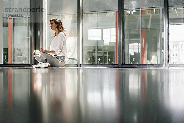 Businesswoman practicing yoga in office  meditating