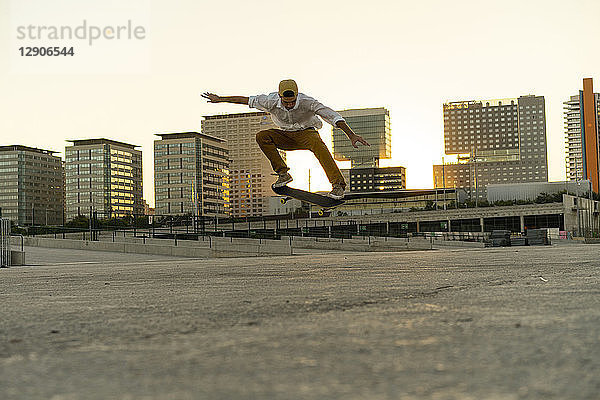 Young man doing a skateboard trick in the city at sunset