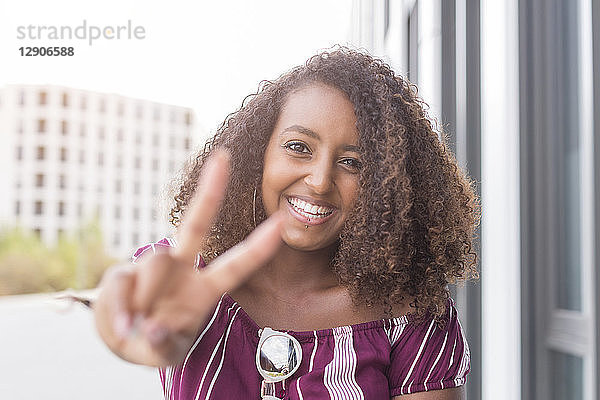 Portrait of smiling young woman showing victory sign