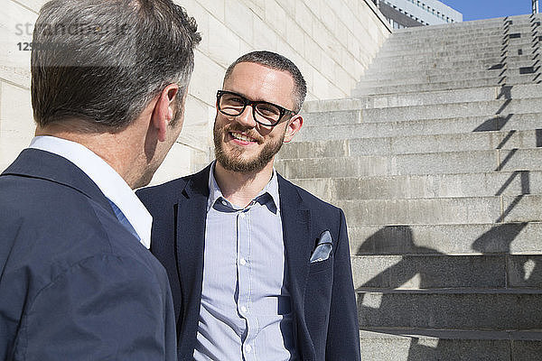 Two businessmen talking at stairs outdoors