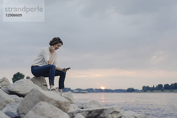 Woman sitting at the river  using smartphone