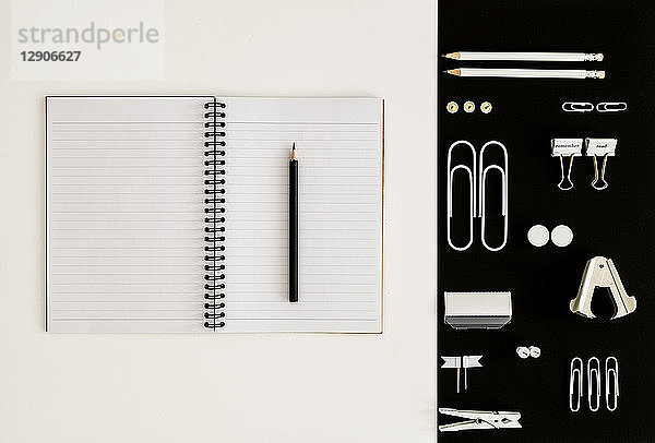White office utensils on black background and notepad and pencil on whilte background