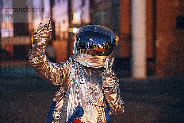 Spaceman in the city at night taking a selfie