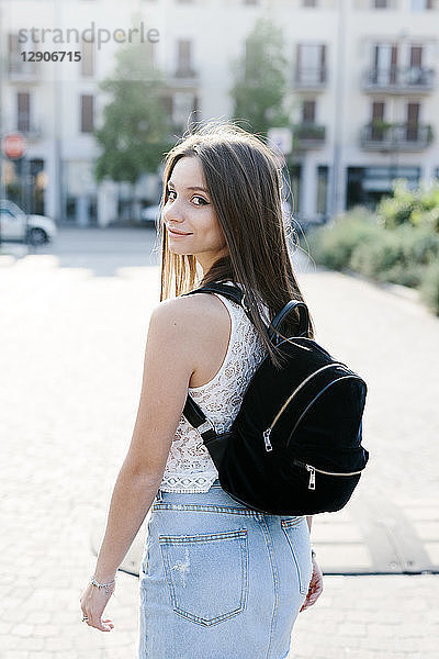 Portrait of smiling young woman with backpack in the city