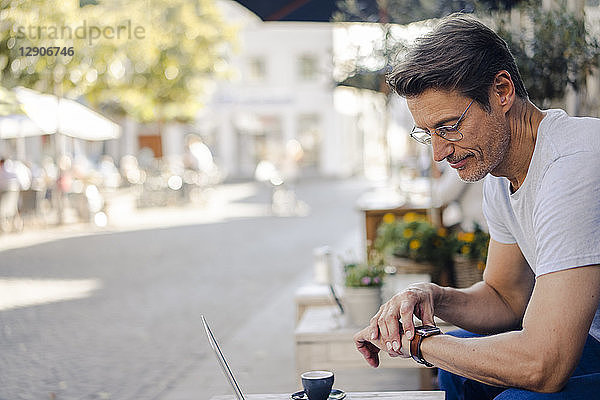 Mature businessman sitting in coffee shop  checking time