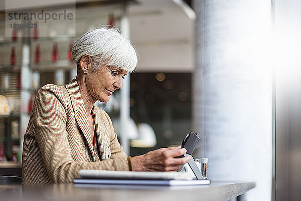 Senior businesswoman using tablet in a cafe