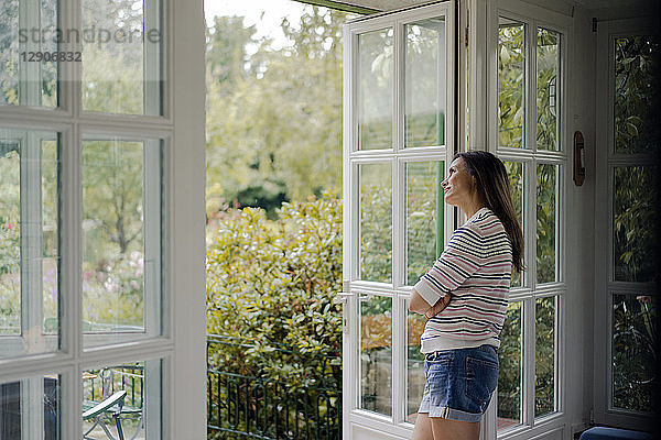 Mature woman looking out of terrace door at home
