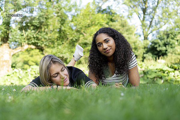 Two girlfriends relaxing in grass in a park
