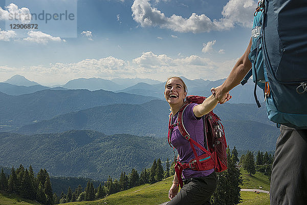 Germany  Bavaria  Brauneck near Lenggries  happy young woman hiking in alpine landscape holding hand of boyfriend