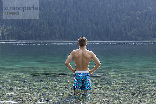 Germany  Bavaria  Eibsee  back view of young man standing in water