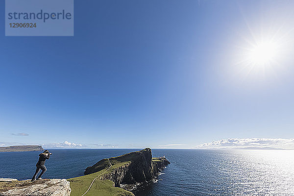 UK  Scotland  Inner Hebrides  Isle of Skye  tourist taking picture of lighthouse at Neist Point