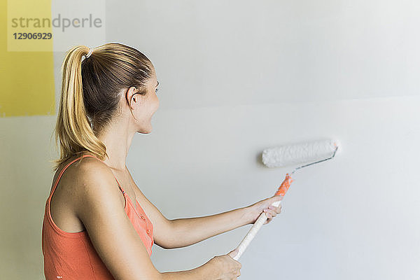 Young woman painting wall at new home