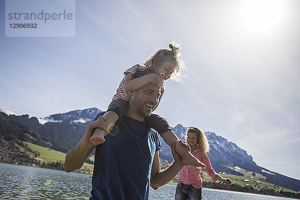 Austria  Tyrol  Walchsee  happy father carrying daughter on shoulders at the lake