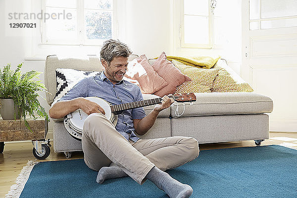 Man sitting on floor  playing the banjo