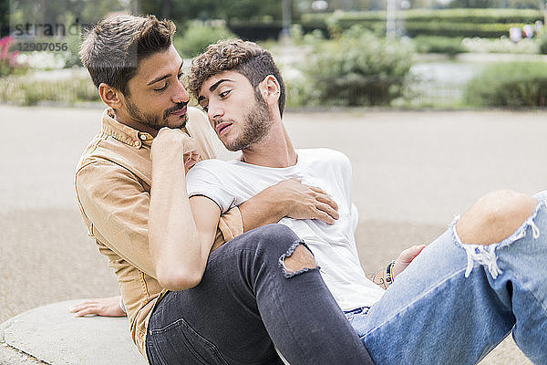Young gay couple relaxing together on bench
