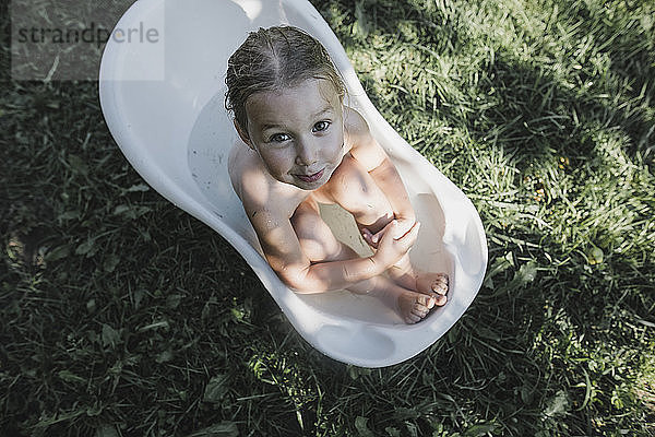 Portrait of little girl sitting in bath tub in garden