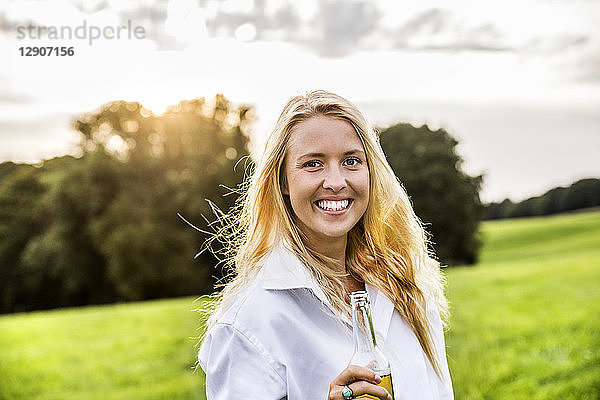 Portait of happy woman drinking beer in rural landscape