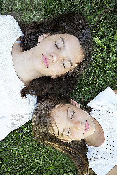 Two sisters resting together on a meadow
