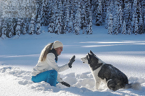Austria  Altenmarkt-Zauchensee  young woman sitting with dog in snow