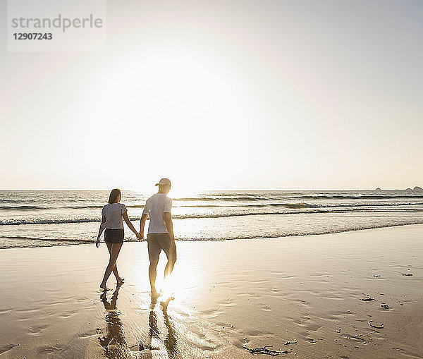 Young couple doing a romantic beach stroll at sunset