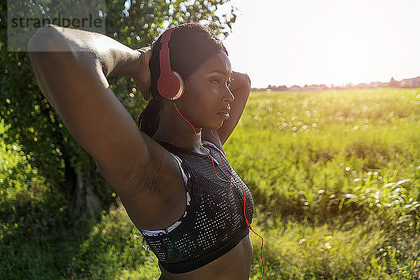 Young athlete in nature  listening music with headphones