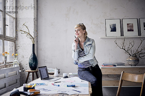 Portrait of smiling woman at desk in a loft