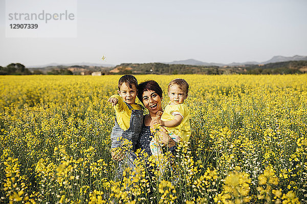 Spain  portrait of laughing mother with little son and daughter in a rape field