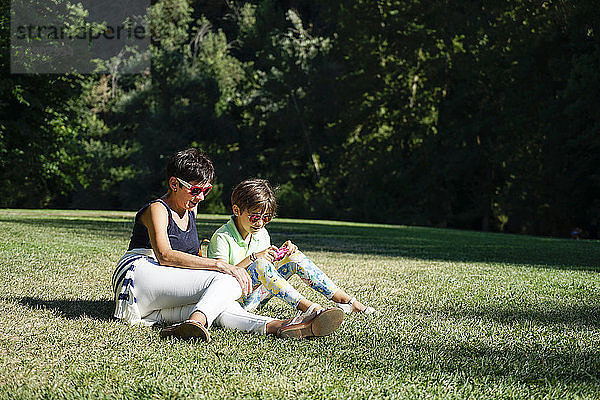 Mother and daughter taking photographs  sitting on grass