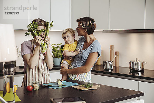 Playful lesbian couple and their child in kitchen