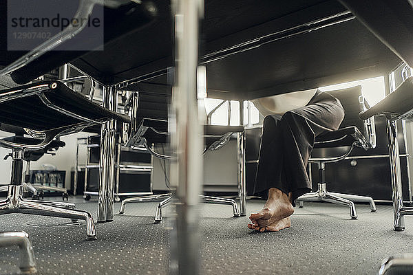 Bare feet of businesswoman under her desk