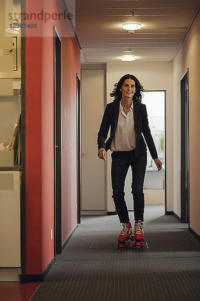 Mature businesswoman rollerskating in office corridor