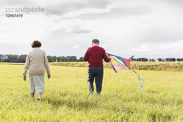 Senior couple walking with kite in rural landscape