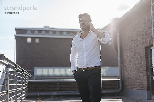 Businessman standing on rooftop terrace  making a phone call