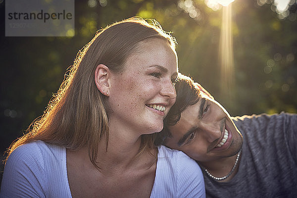 Romantic young couple sitting in park  enjoying sunset