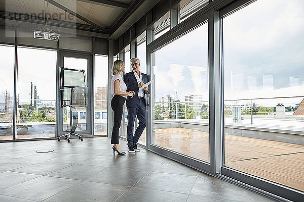 Businessman and woman standing in office  discussing project  holding documents