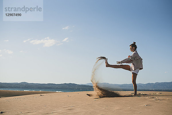 Teenage girl throwing sand on the beach