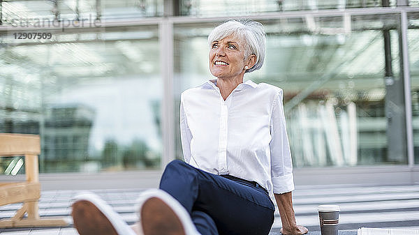 Smiling senior businesswoman sitting outside looking around