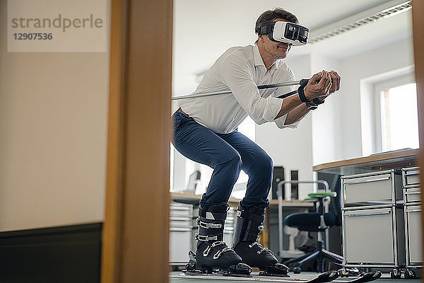 Businessman skiing in office  using VR glasses