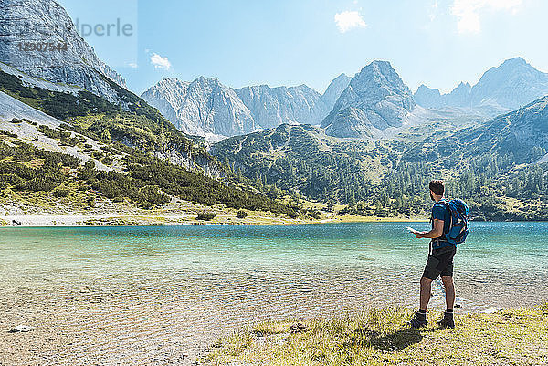 Austria  Tyrol  Man hiking at Seebensee Lake  looking at map