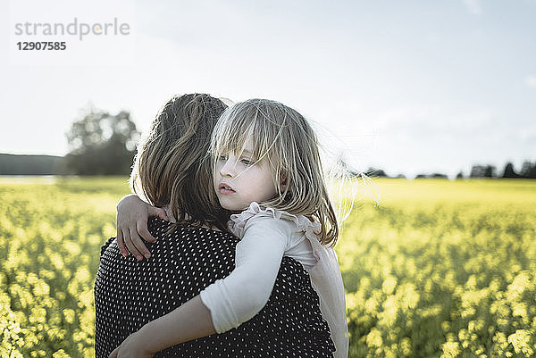 Portrait of little girl on her mother's arms in rape field