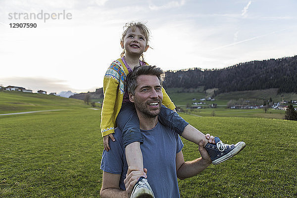 Austria  Tyrol  Walchsee  happy father carrying daughter piggyback on an alpine meadow