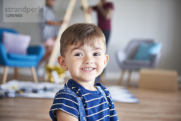 Portrait of smiling boy at home with parents in background