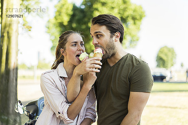 Couple with motor scooter in summer sharing ice cream