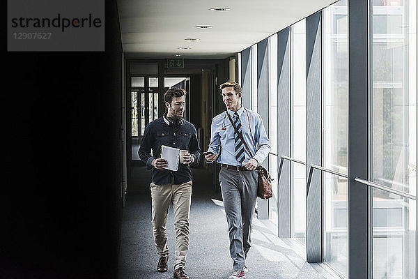 Two colleagues walking and talking on office floor