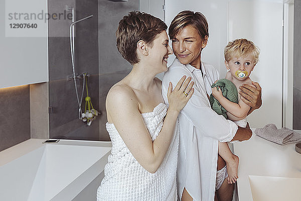 Happy lesbian couple and their little son in the bathroom