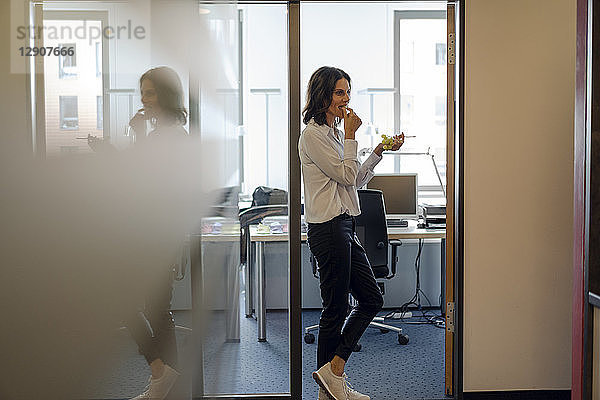 Businesswoman standing in office  eating grapes