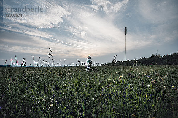 Spaceman exploring nature  standing in meadow  looking at sky